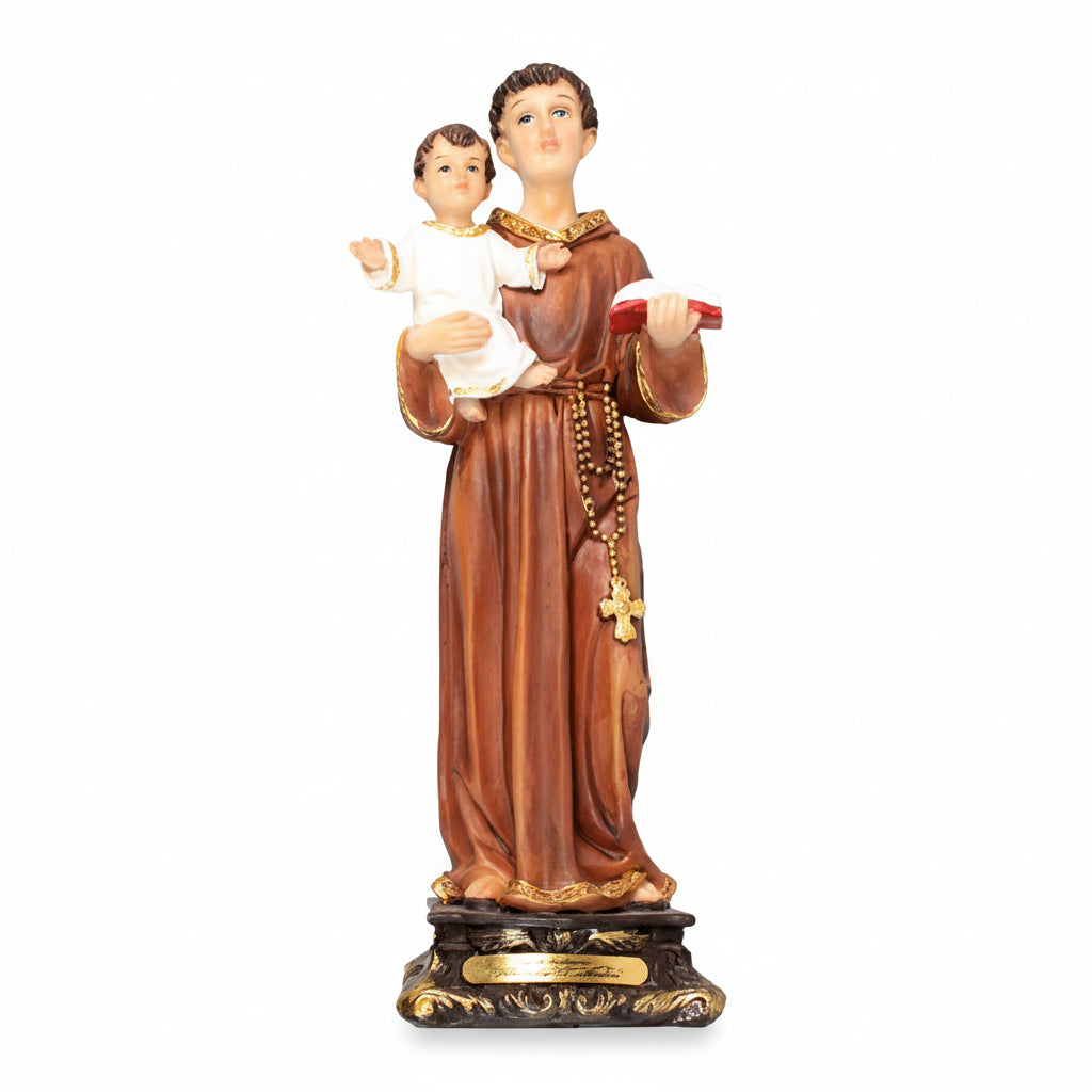 A resin statue of Saint Anthony holding a child, gold-colored details and a cross on a black base.