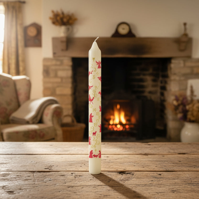 An advent nativity candle with numbers from 1 to 24 and a depiction of the nativity scene in the background. The candle is white with red numbers and figures.