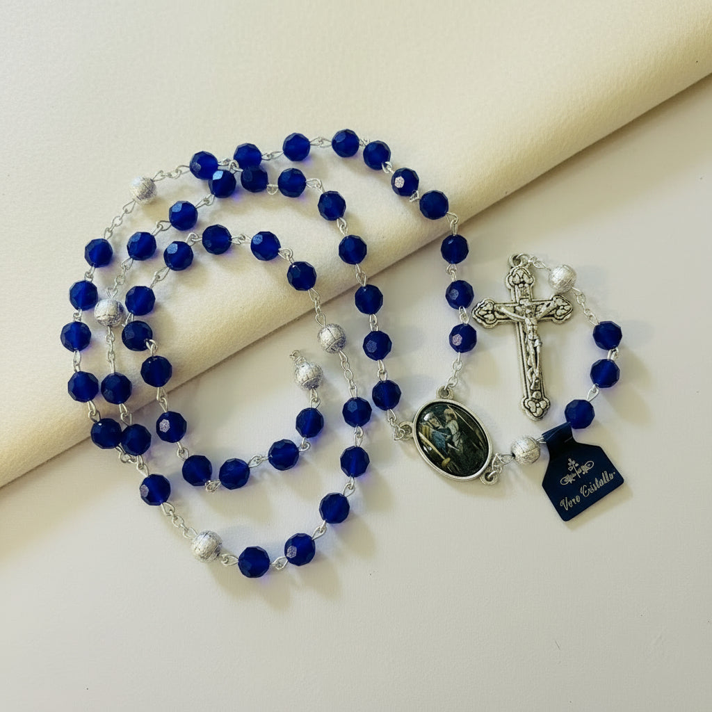 Blue rosary with a cross and medal on a light background