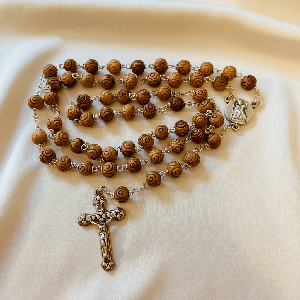 A carved olivewood rosary with silver accents and a cross pendant.