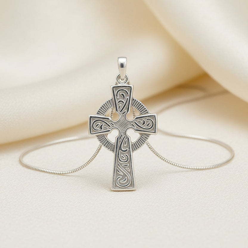 Silver cross pendant on a beige fabric background