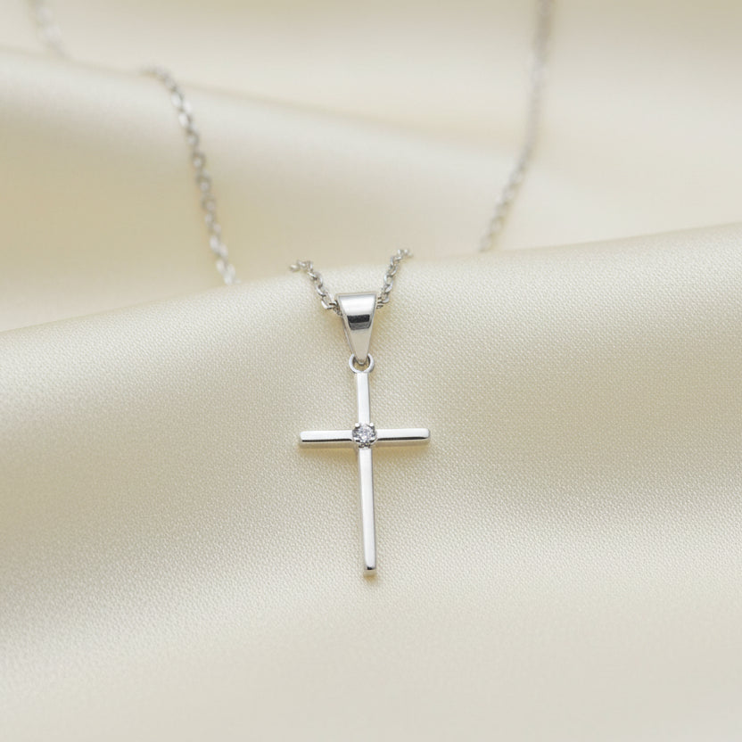 A silver cross pendant necklace against a white background.