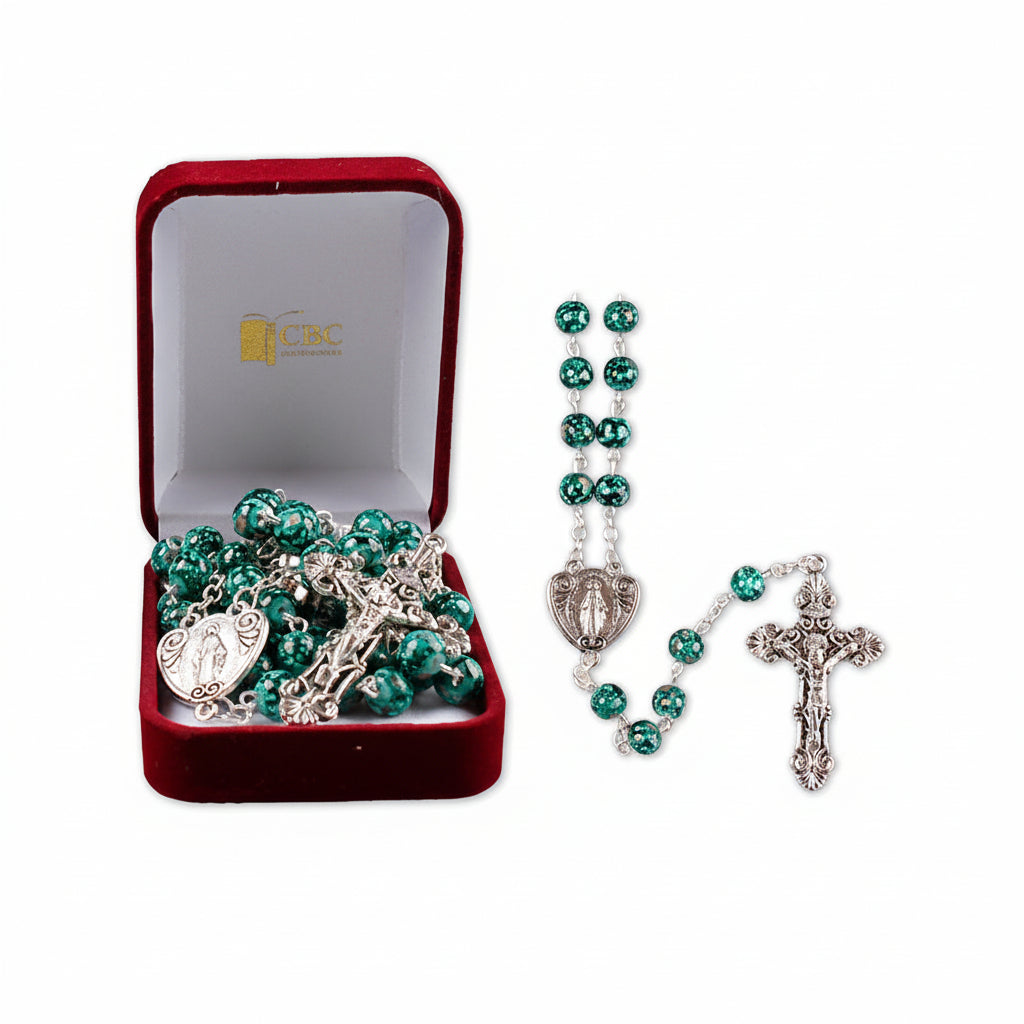 A dark green two-tone glass rosary displayed in an open red velvet box with the Vatican City emblem, featuring a metal cross and Our Fathers Miraculous metal junction.