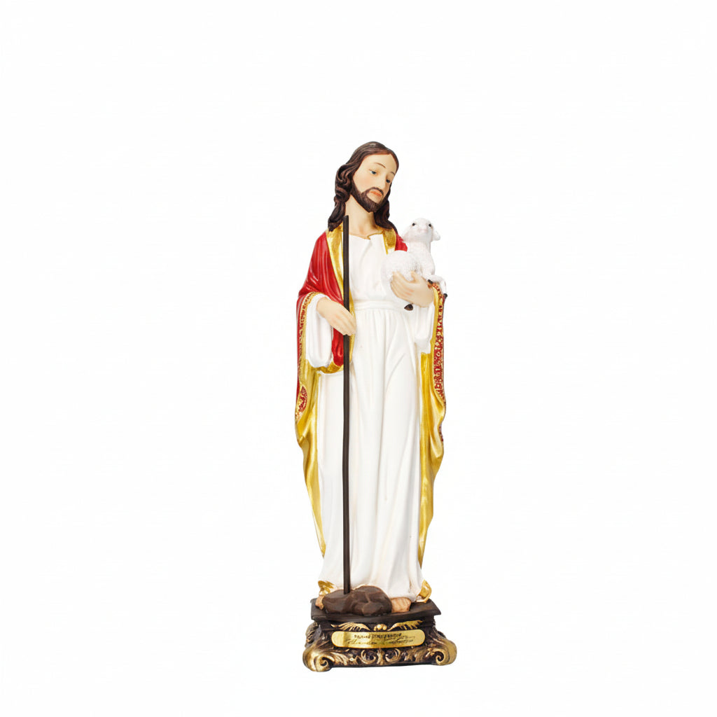 A resin statue of the Good Shepherd with gold highlights, red and white robes, and a sheep on his shoulders. The statue is mounted on a base with gold accents.