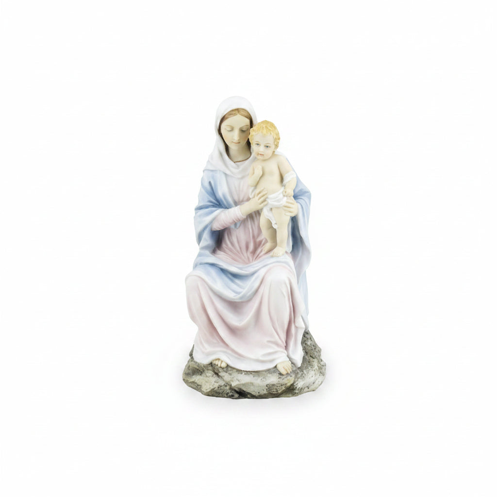 A religious figurine of the Virgin Mary holding the infant Jesus, painted in soft pastel shades of blue, pink, and white, standing on a textured gray rock base against a plain white background.