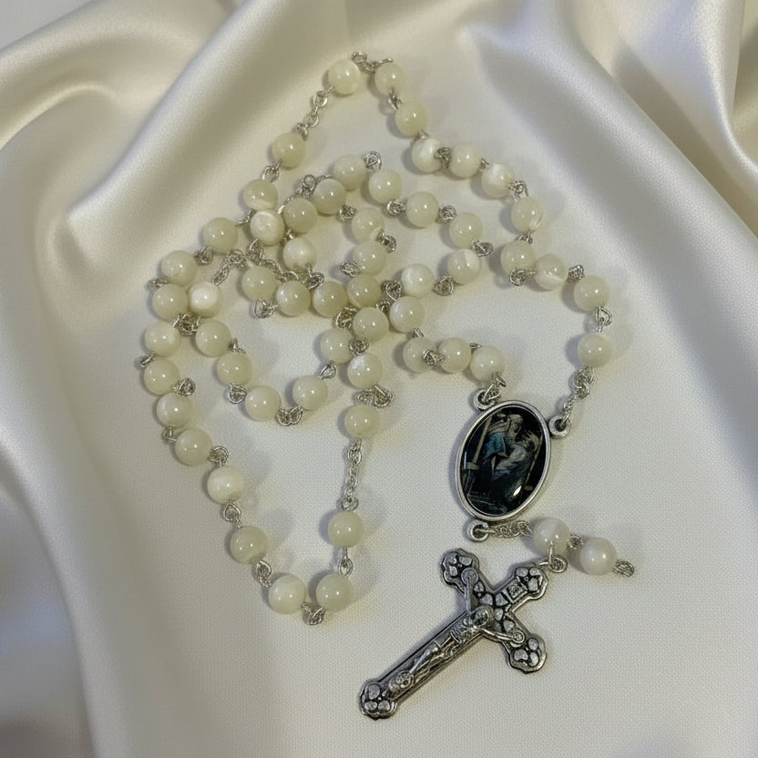 Rosary with white beads and silver cross on a light gray background