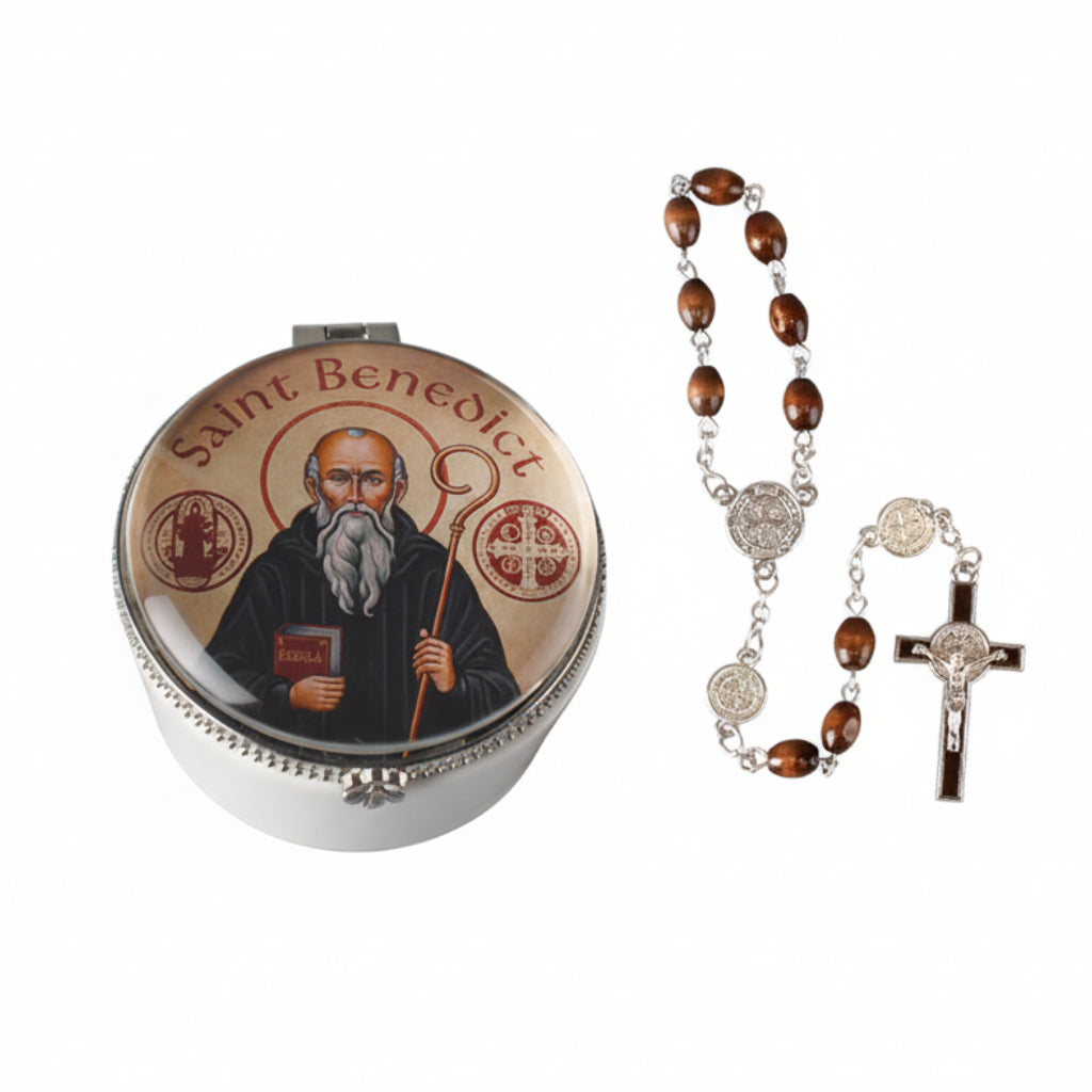 A porcelain rosary box with a picture glass dome lid featuring St. Benedict, a metal frame, and a set of rosary beads with a cross.