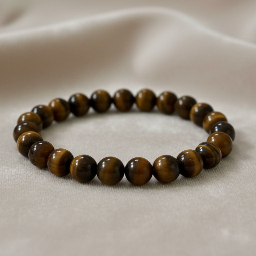 A Tiger Eye bracelet on a beige background, displayed on a brown card with the text 'POWER BRACELETS - TIGER EYE - OVERCOMING FEAR'.