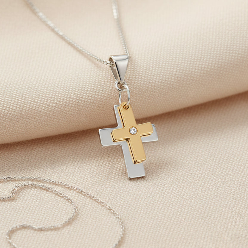 Two-tone cross pendant on a beige fabric background