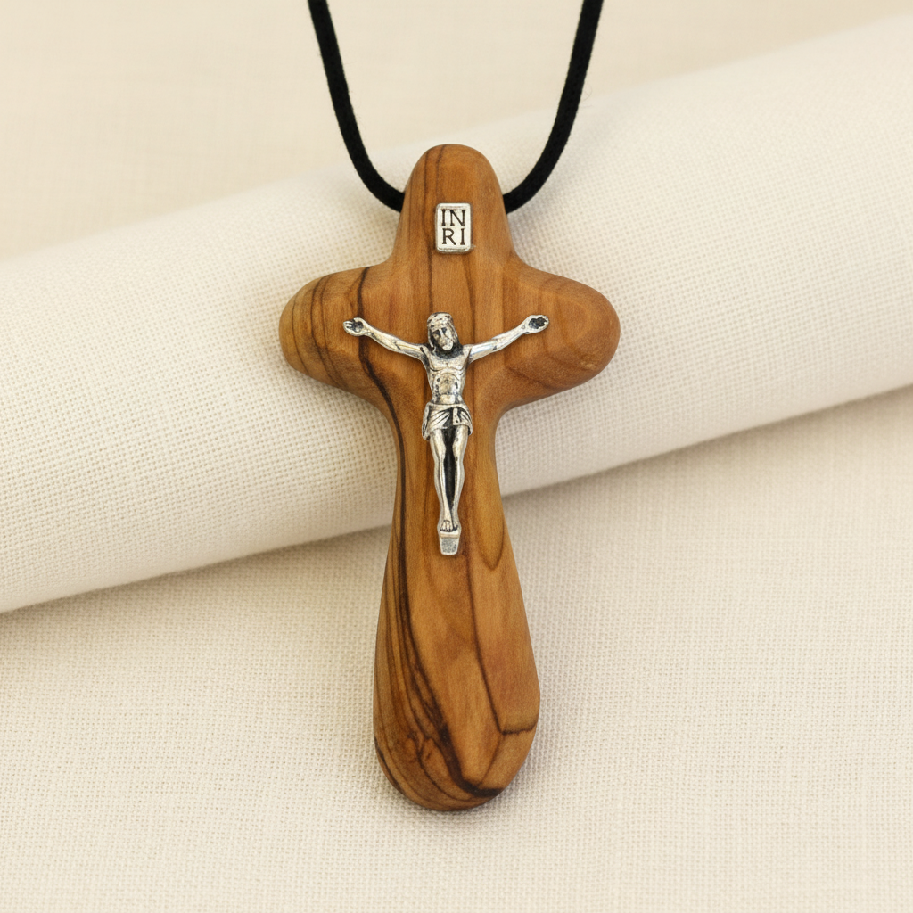 A wooden crucifix pendant necklace with a black cord. The pendant features a relief sculpture of a crucifixion scene.