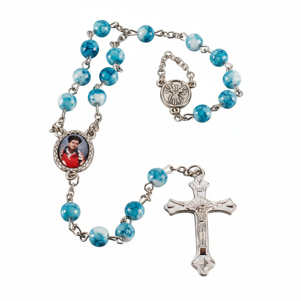 Blue rosary with silver cross and images of a person on gray background