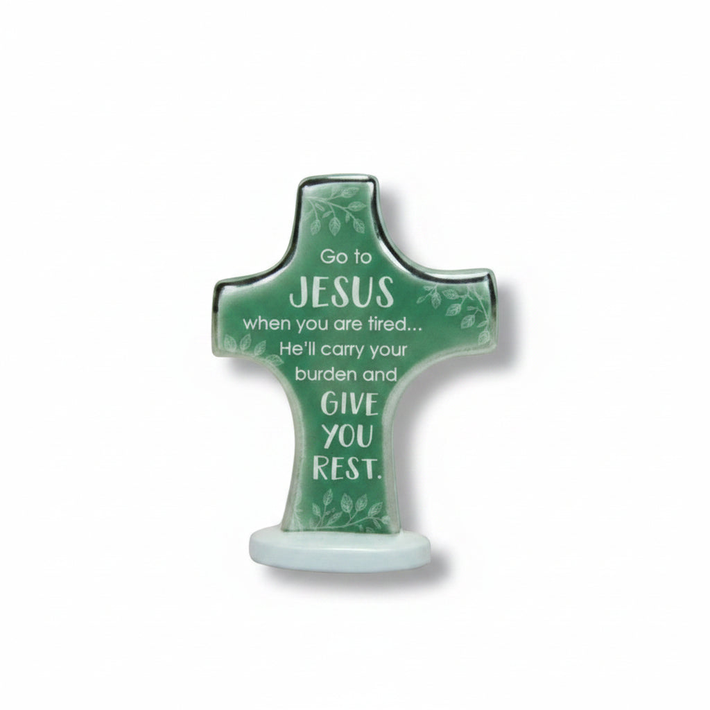 A decorative cross-shaped sign with a green top and white base, featuring the words 'BEDTIME PRAYERS' at the top and a prayer printed on the cross, set against a textured tan background with small white stars.