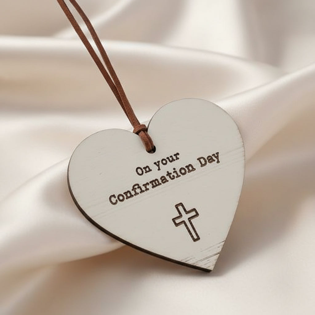 A wooden heart-shaped decoration with a hanging loop, a cross emblem, and the text 'On your Confirmation Day'.