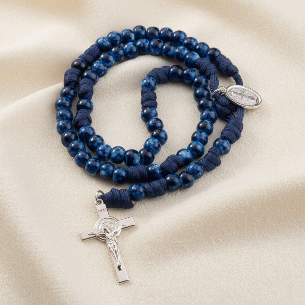 Blue rosary with silver crucifix on a white background with st benedicts medal