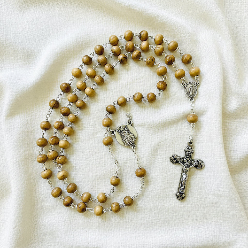 A carved olivewood rosary with beige beads and a silver-colored cross on a white background.