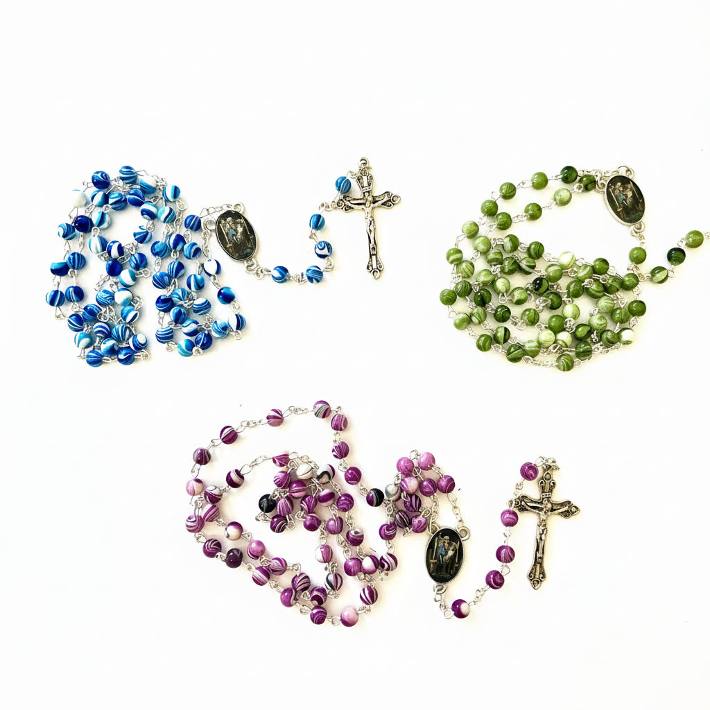 Three rosaries in blue, green, and purple on a white surface