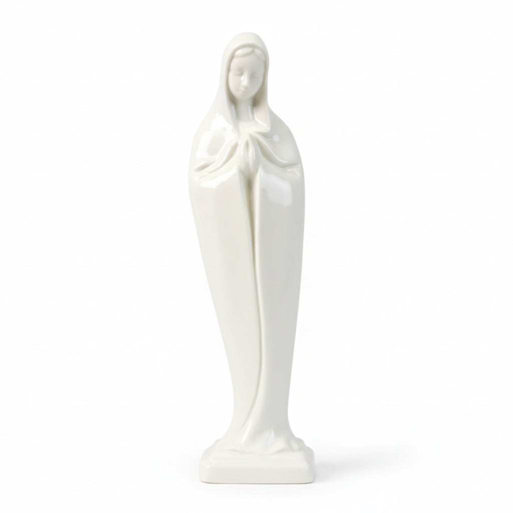 A white porcelain statue of the Madonna, depicting the figure of Mary with a simple pose, wearing a veil, against a dark background.