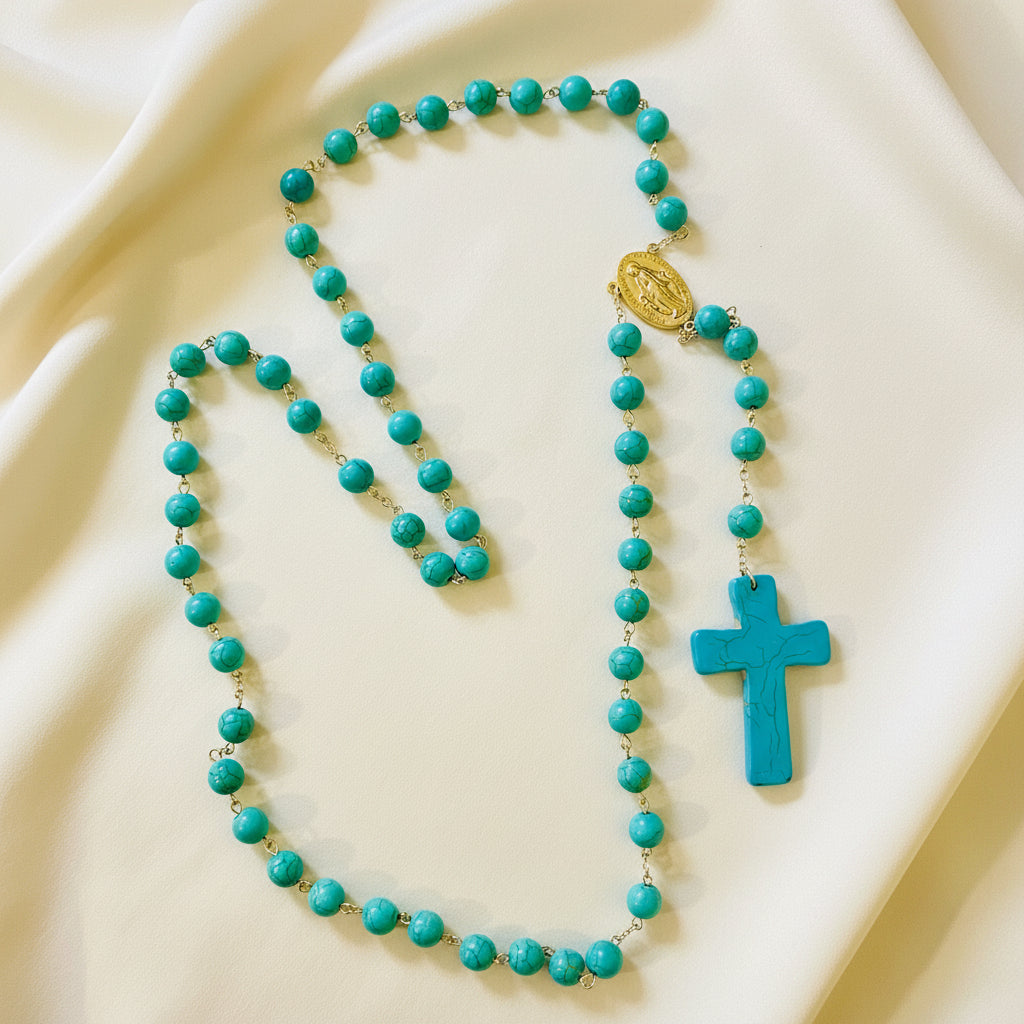 A turquoise ceramic rosary with a cross and beads displayed against a white background.