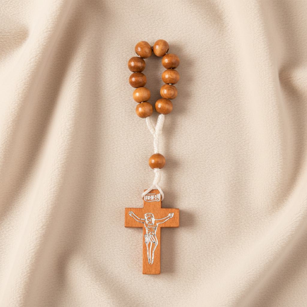 A wooden finger rosary with a cross and Jesus figure on the bottom, white cord, and brown wooden beads.