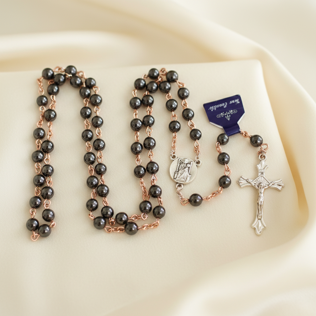 A black rosary with large beads and silver links, featuring a cross and a small circular centerpiece.
