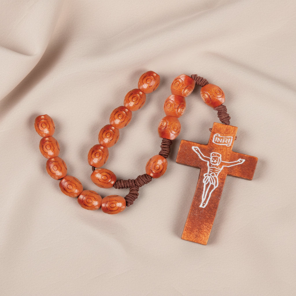 A set of natural wooden rosary beads featuring a brown cross with an engraved figure of Jesus Christ in the center.
